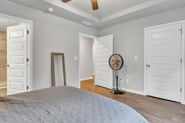 bedroom featuring a tray ceiling, ceiling fan, and hardwood / wood-style flooring