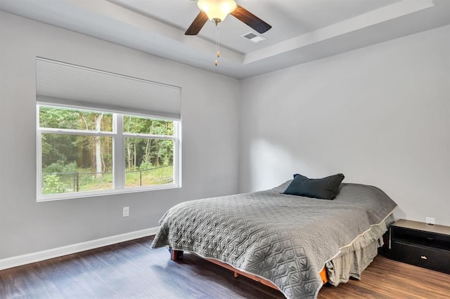 bedroom with a tray ceiling, ceiling fan, and hardwood / wood-style floors