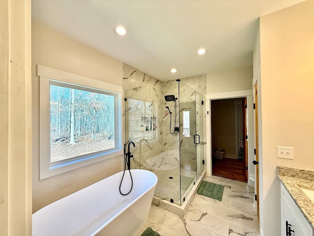 full bath featuring marble finish floor, recessed lighting, a freestanding bath, a stall shower, and vanity