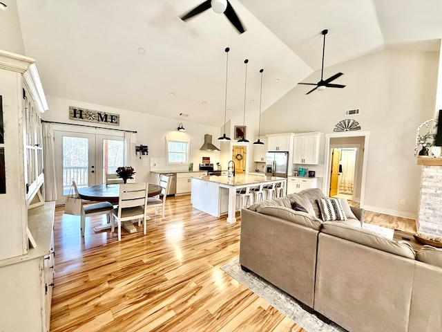 living room with visible vents, french doors, light wood-style flooring, and a ceiling fan