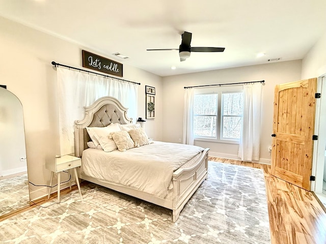 bedroom with baseboards, visible vents, arched walkways, and wood finished floors