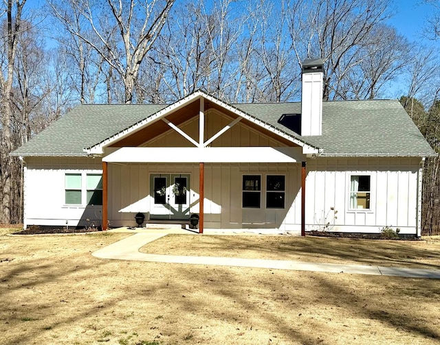 back of house with french doors, a chimney, a shingled roof, covered porch, and board and batten siding