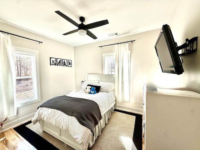 bedroom with baseboards, visible vents, ceiling fan, and light wood finished floors