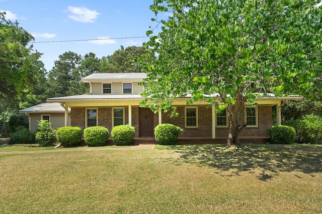 view of front of house with a porch, a front yard, brick siding, and metal roof