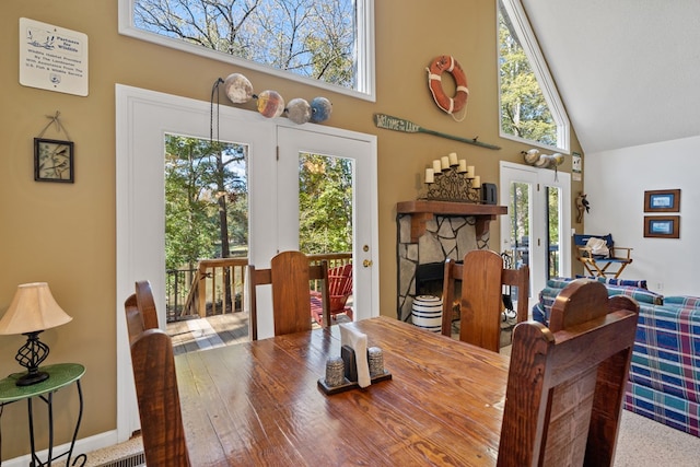 dining area with a fireplace and high vaulted ceiling