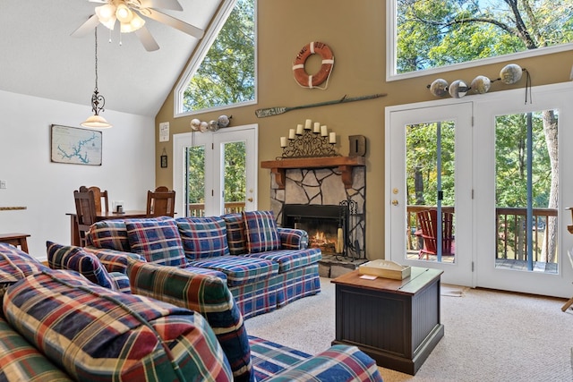 living room featuring a textured ceiling, light colored carpet, ceiling fan, high vaulted ceiling, and a stone fireplace