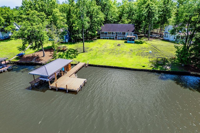 dock with a water view, boat lift, and a lawn