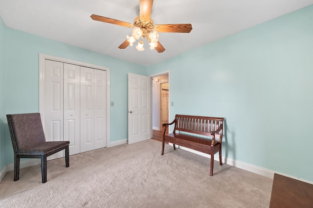 living area featuring baseboards, light carpet, and a ceiling fan