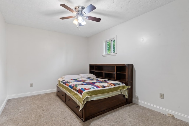 carpeted bedroom featuring baseboards, ceiling fan, and a textured ceiling