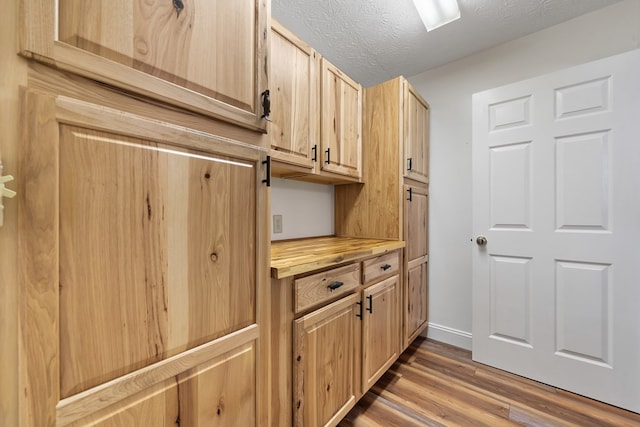 detailed view of wood finished floors, a textured ceiling, and baseboards