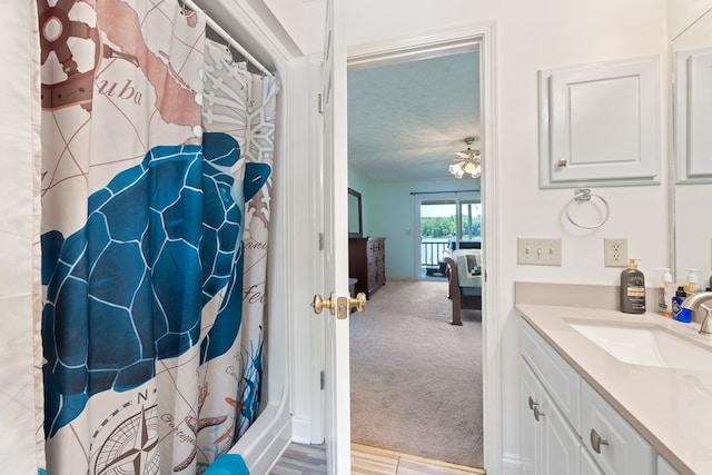 ensuite bathroom featuring vanity, ceiling fan, a shower with curtain, and a textured ceiling
