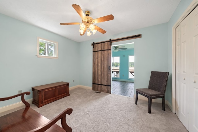 sitting room with plenty of natural light, a barn door, carpet, and ceiling fan