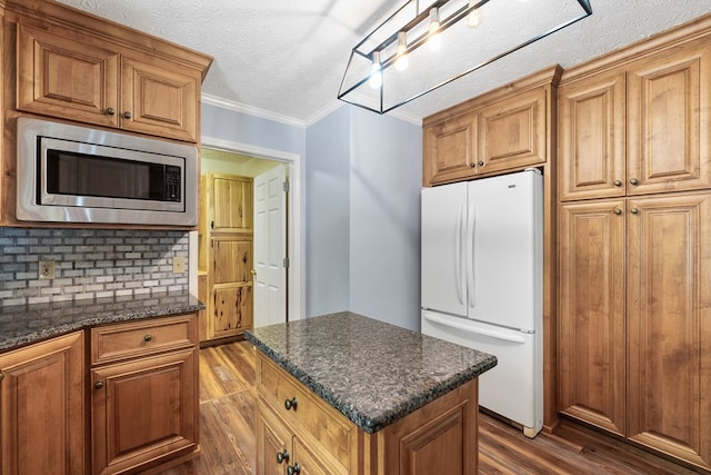 kitchen with freestanding refrigerator, stainless steel microwave, dark wood-style flooring, a kitchen island, and a textured ceiling