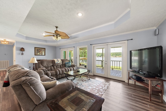 living area with a tray ceiling, french doors, a textured ceiling, wood finished floors, and a ceiling fan