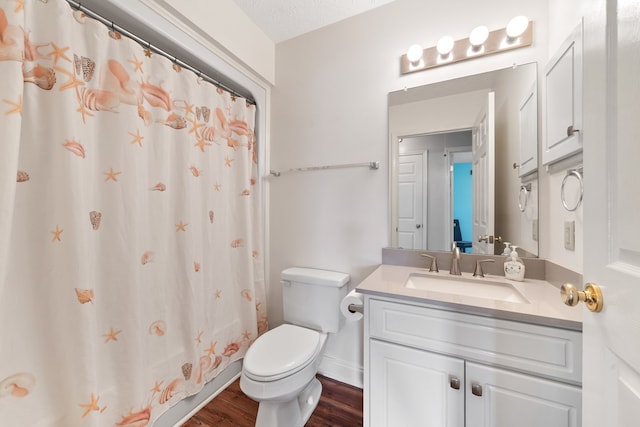 bathroom with wood finished floors, toilet, vanity, and curtained shower