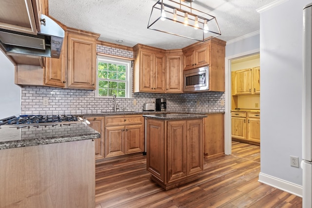 kitchen with a sink, appliances with stainless steel finishes, ornamental molding, a textured ceiling, and decorative backsplash