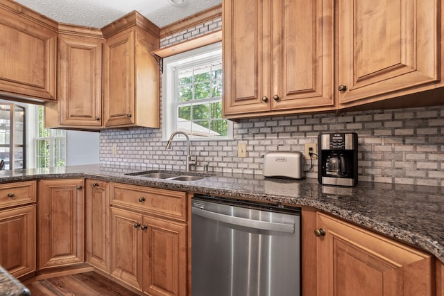 kitchen featuring dishwasher, a sink, tasteful backsplash, and brown cabinetry