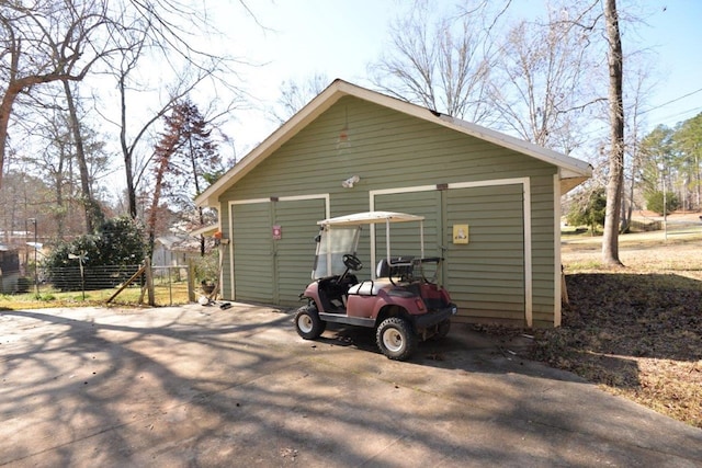 view of outdoor structure featuring an outbuilding, driveway, fence, and a carport