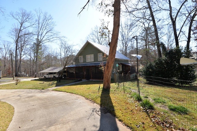 view of front of house featuring a front lawn, fence, a porch, metal roof, and driveway