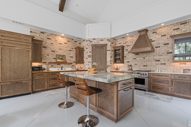 2163 N Jefferson St, Milledgeville, GA 31061 - kitchen featuring custom exhaust hood, premium stove, a center island, decorative backsplash, and a breakfast bar area