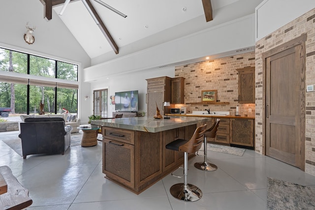 2163 N Jefferson St, Milledgeville, GA 31061 - kitchen featuring high vaulted ceiling, beam ceiling, a center island, a kitchen breakfast bar, and brown cabinets