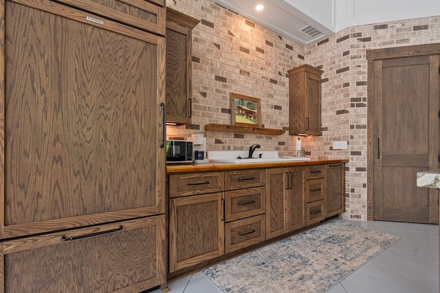 2163 N Jefferson St, Milledgeville, GA 31061 - kitchen featuring black microwave, light countertops, brown cabinets, and brick wall