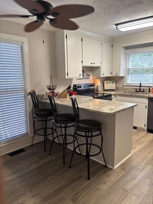 kitchen with range with electric stovetop, a peninsula, white cabinetry, light wood-style floors, and ornamental molding