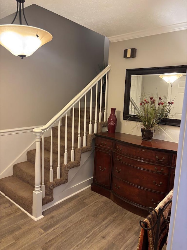 stairway featuring wood finished floors, ornamental molding, and baseboards