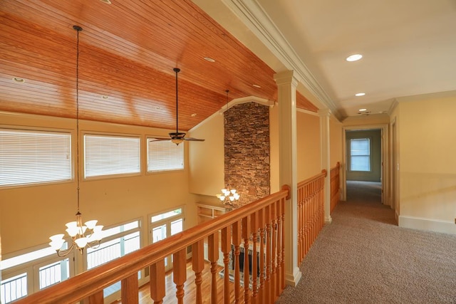 hall featuring carpet, ornamental molding, wood ceiling, a notable chandelier, and an upstairs landing