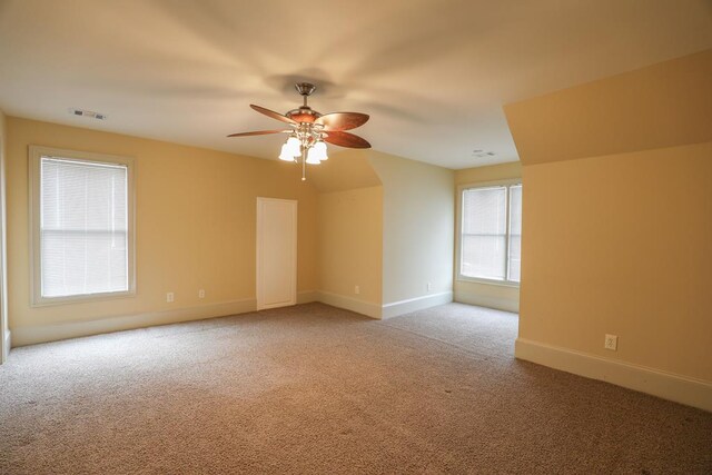 spare room with baseboards, light colored carpet, visible vents, and ceiling fan