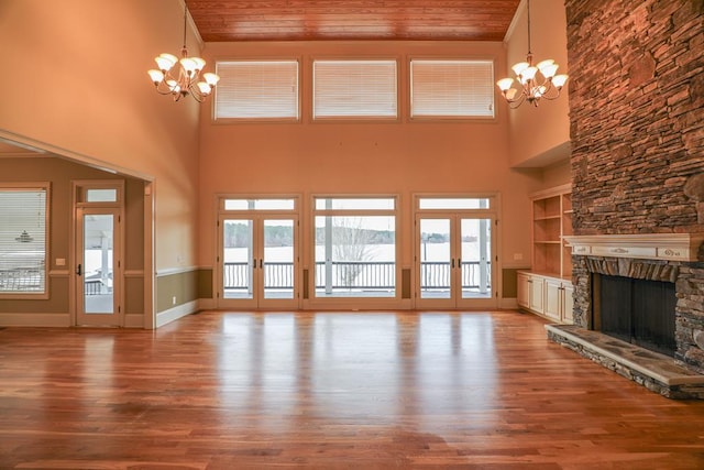 unfurnished living room featuring french doors, a fireplace, wooden ceiling, and an inviting chandelier