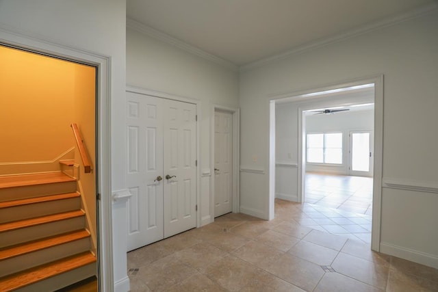 corridor featuring stairs, light tile patterned flooring, baseboards, and ornamental molding