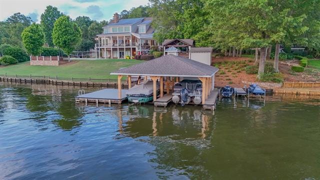 view of dock featuring boat lift, a lawn, and a water view