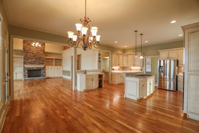 kitchen with a kitchen island, open floor plan, an inviting chandelier, wood finished floors, and stainless steel appliances