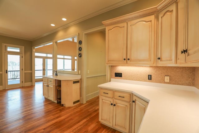 kitchen with decorative backsplash, wood finished floors, crown molding, and light countertops