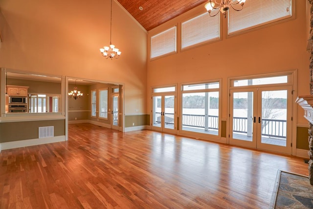 unfurnished living room with visible vents, baseboards, a chandelier, french doors, and wood finished floors