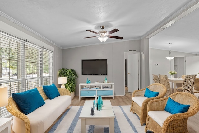 living room with a textured ceiling, ceiling fan, light wood-type flooring, and crown molding