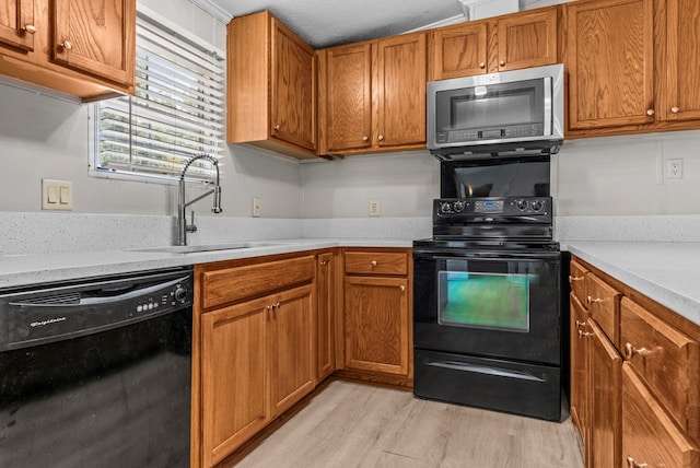 kitchen featuring sink, light hardwood / wood-style flooring, and black appliances