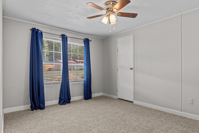 carpeted empty room with a textured ceiling, ceiling fan, and ornamental molding