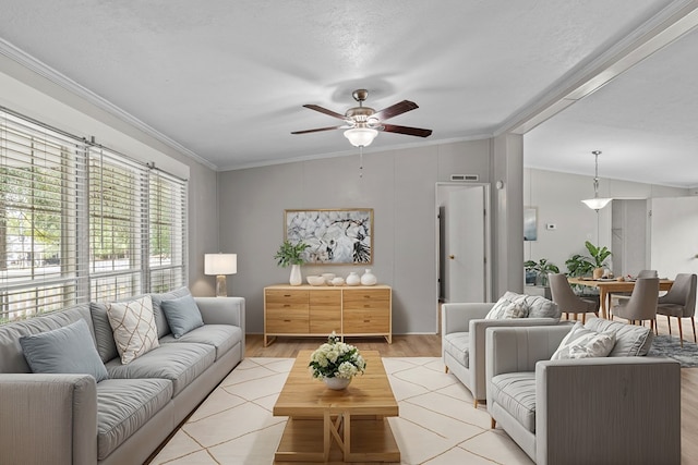 living room featuring ceiling fan, light hardwood / wood-style floors, ornamental molding, and a textured ceiling