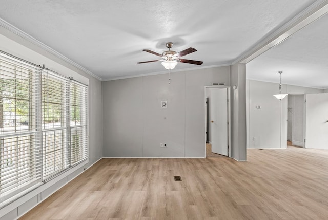 empty room with a textured ceiling, light wood-type flooring, ceiling fan, and crown molding