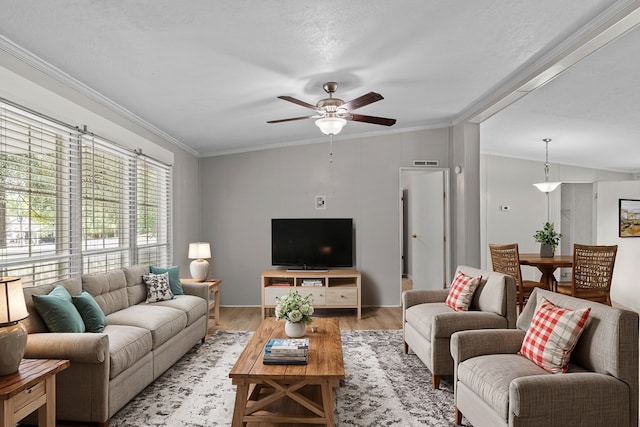 living room featuring a textured ceiling, ceiling fan, light wood-type flooring, and crown molding