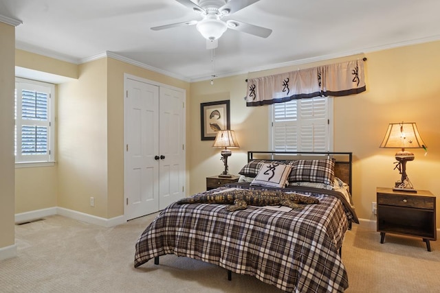 bedroom with ceiling fan, a closet, light colored carpet, and ornamental molding