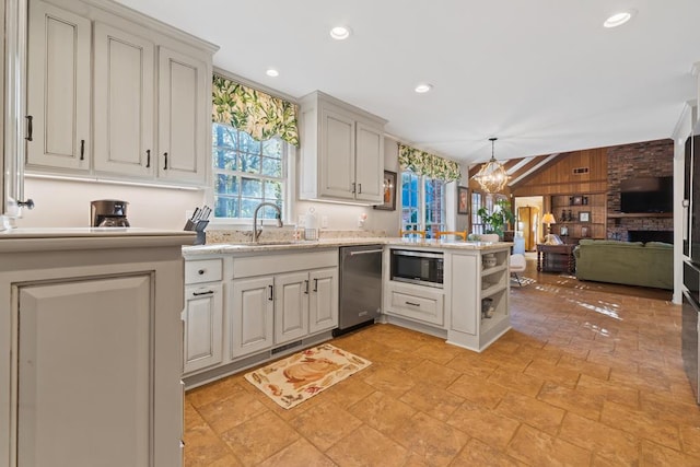 kitchen featuring stainless steel appliances, sink, decorative light fixtures, a fireplace, and lofted ceiling