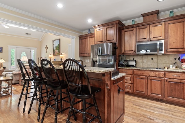411 Rockville Rd, Eatonton, GA 31024 - kitchen with stainless steel appliances, light wood-type flooring, a kitchen bar, light stone counters, and ornamental molding