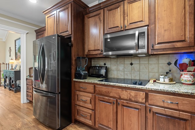 411 Rockville Rd, Eatonton, GA 31024 - kitchen with appliances with stainless steel finishes, light wood-style floors, crown molding, and brown cabinets