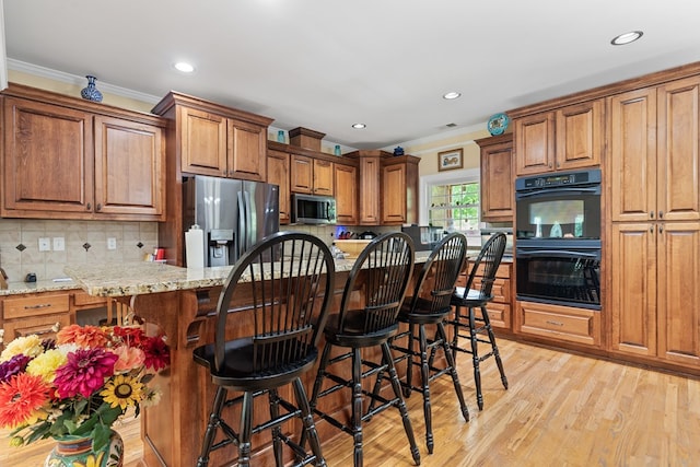 411 Rockville Rd, Eatonton, GA 31024 - kitchen featuring stainless steel appliances, crown molding, brown cabinetry, tasteful backsplash, and a kitchen bar