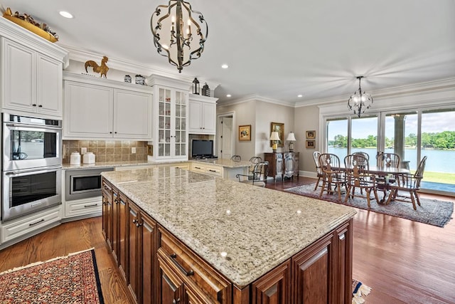 kitchen with decorative light fixtures, a kitchen island, white cabinetry, and stainless steel appliances