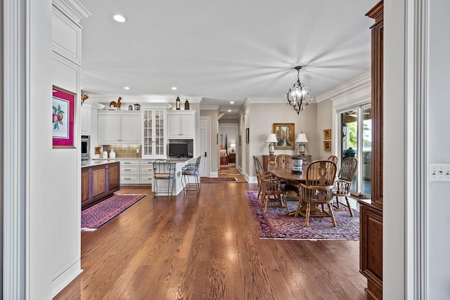 dining area featuring hardwood / wood-style floors, ornamental molding, and a notable chandelier