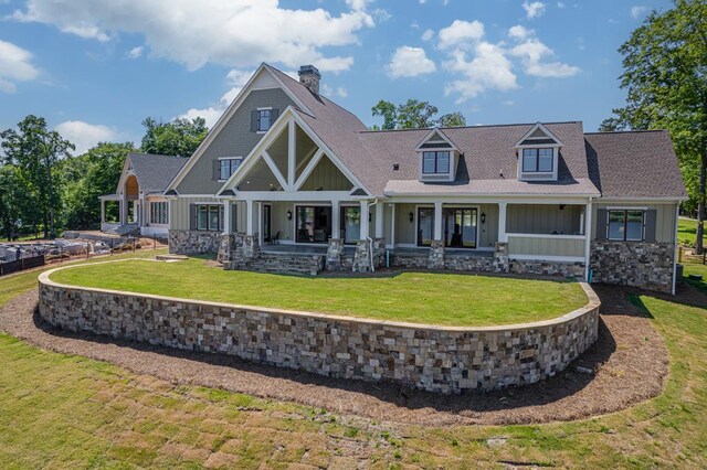 rear view of property with covered porch and a yard
